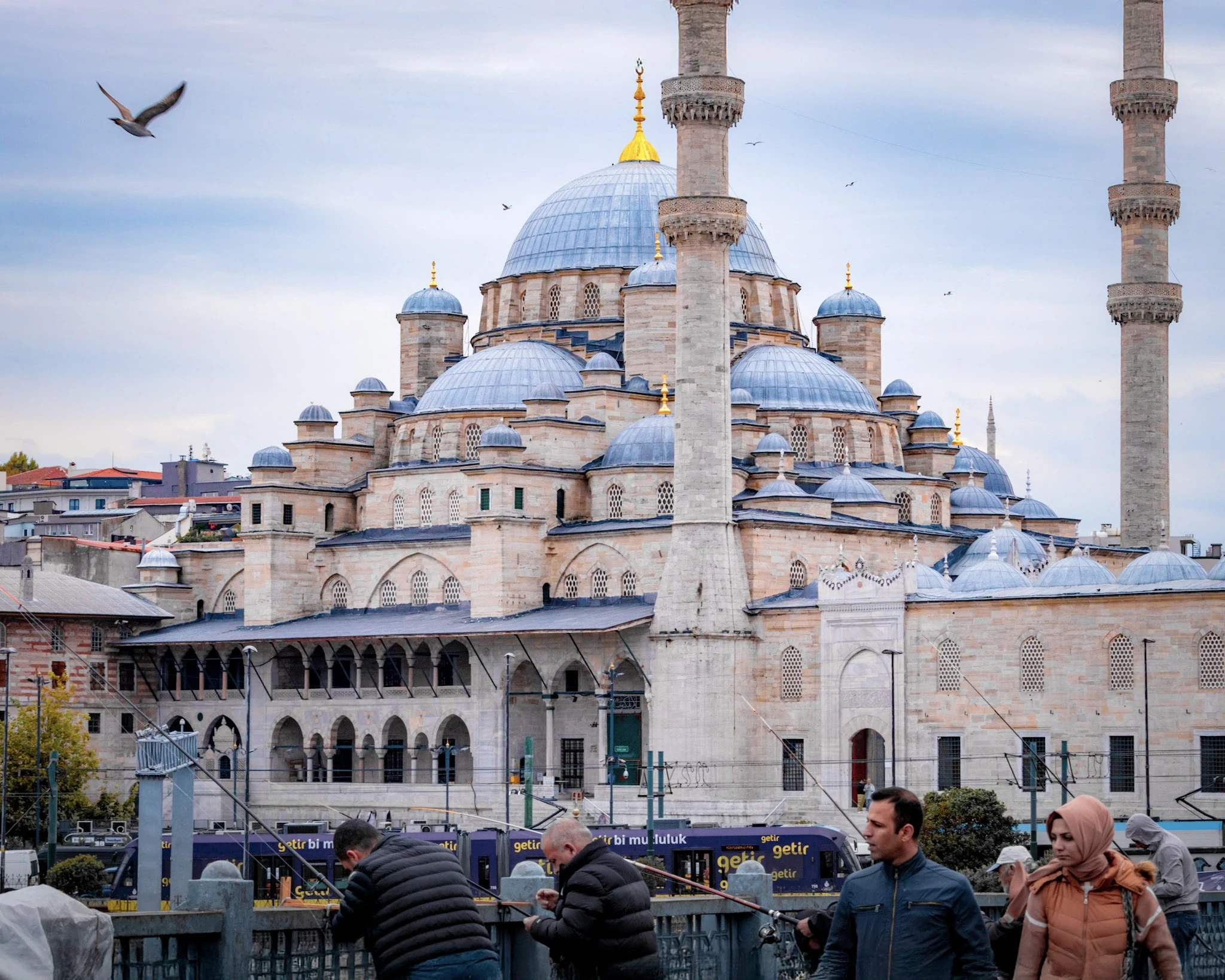The layered domes and slender minarets of a mosque against a blue sky.