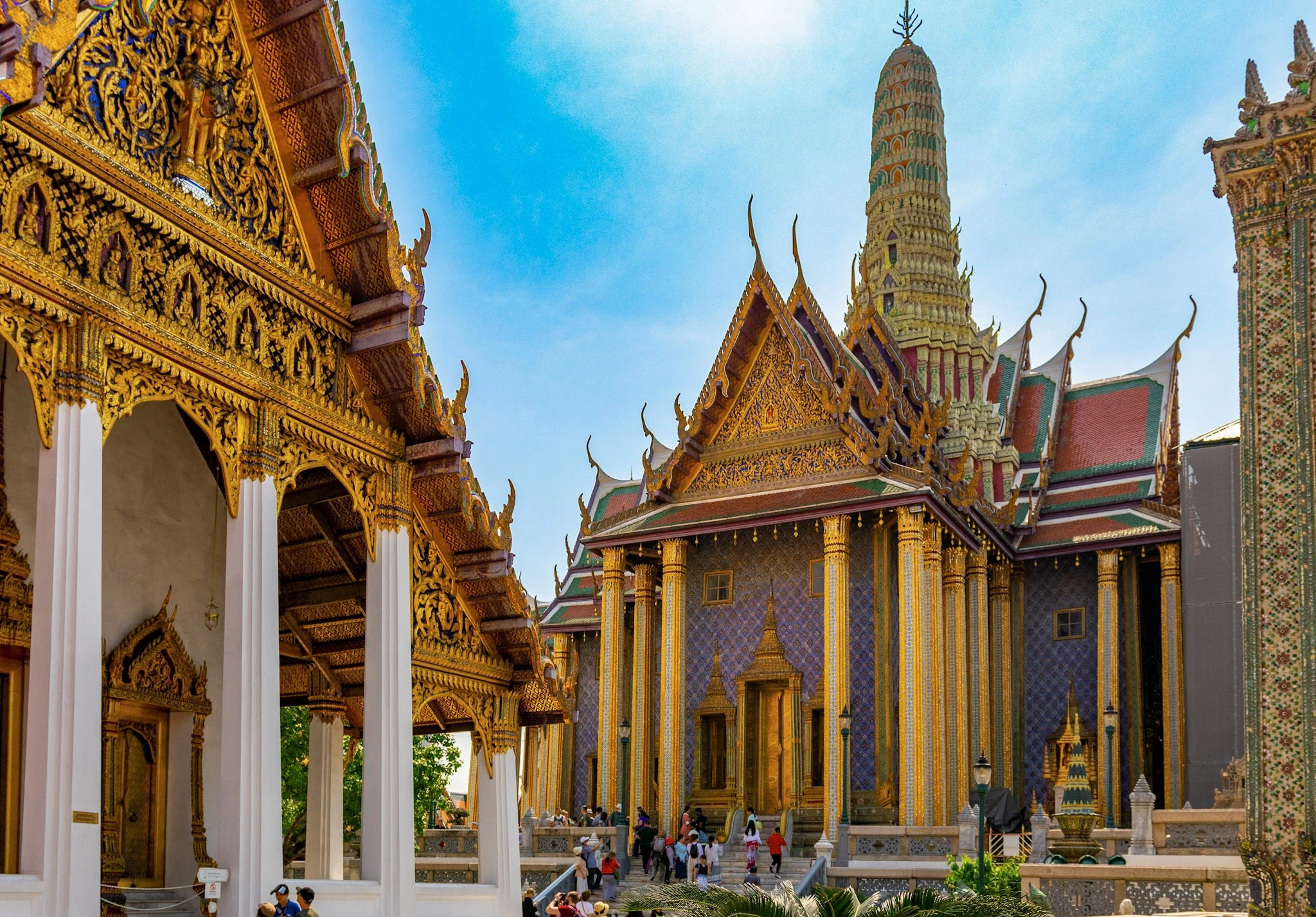 Gilded columns and ornate temple roofs beneath a bright blue sky.