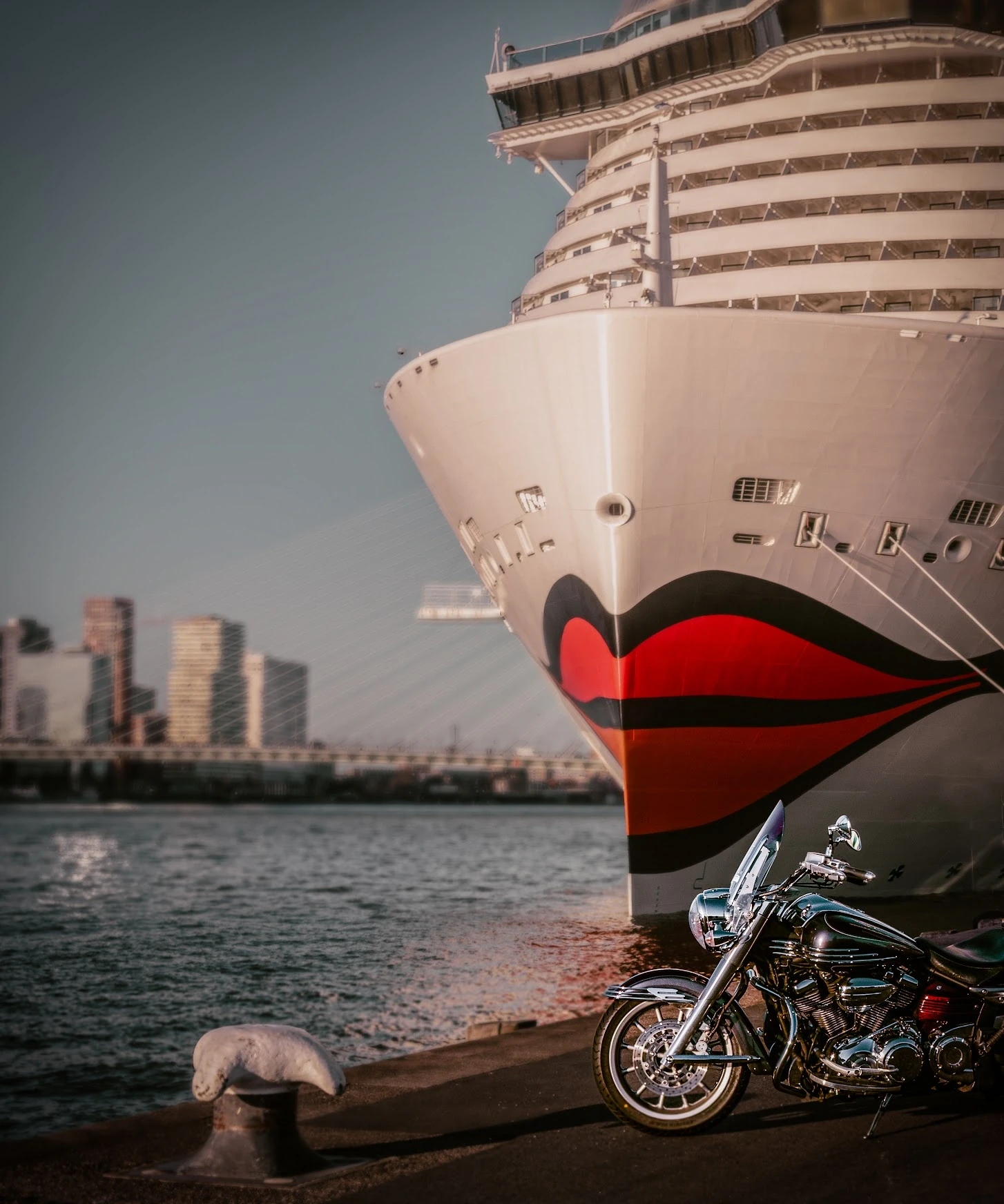 A bicycle beside the towering bow of a ship at the waterfront.