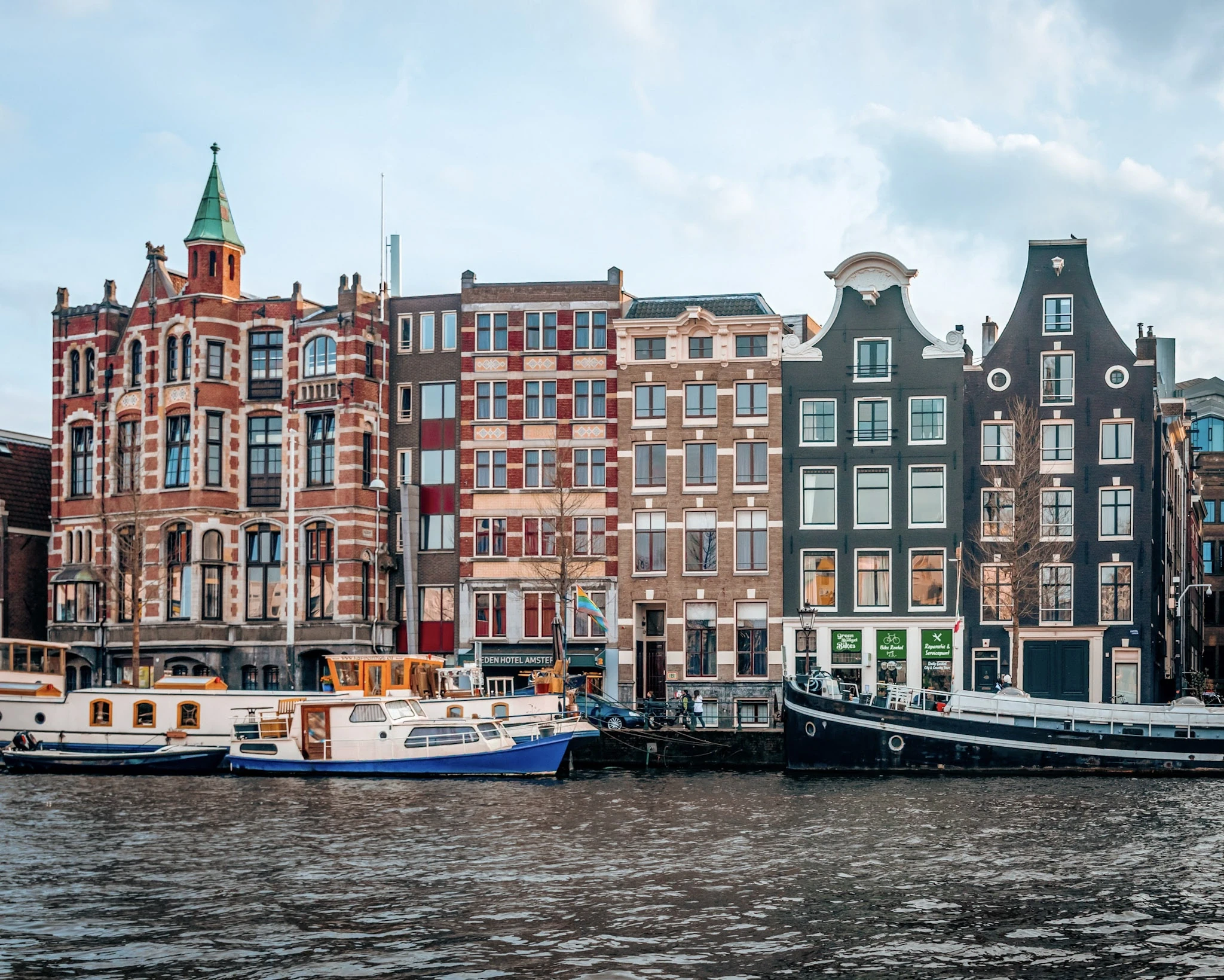 A row of narrow Amsterdam canal houses reflected in the water.
