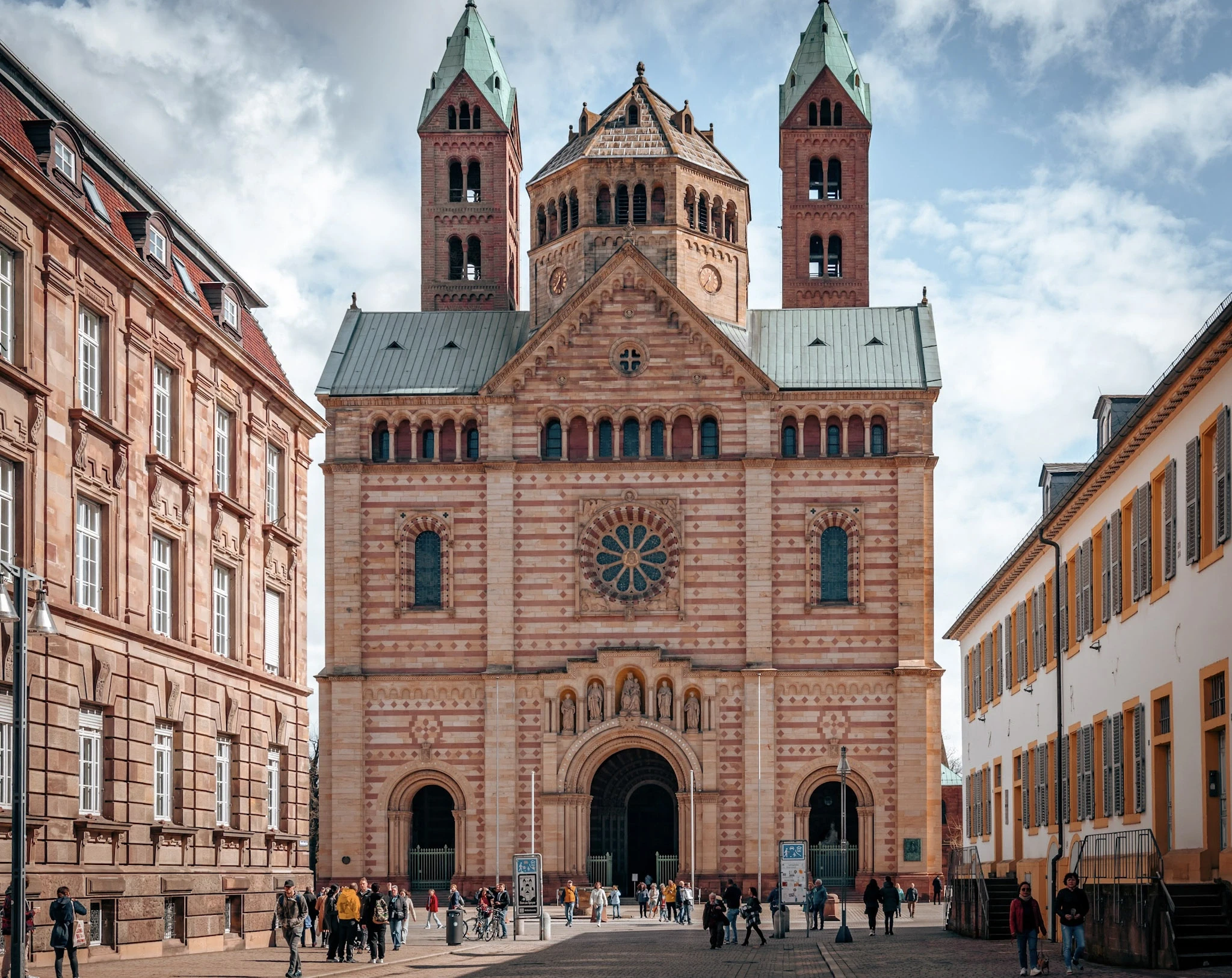 A twin-towered brick church framed by old-town buildings.
