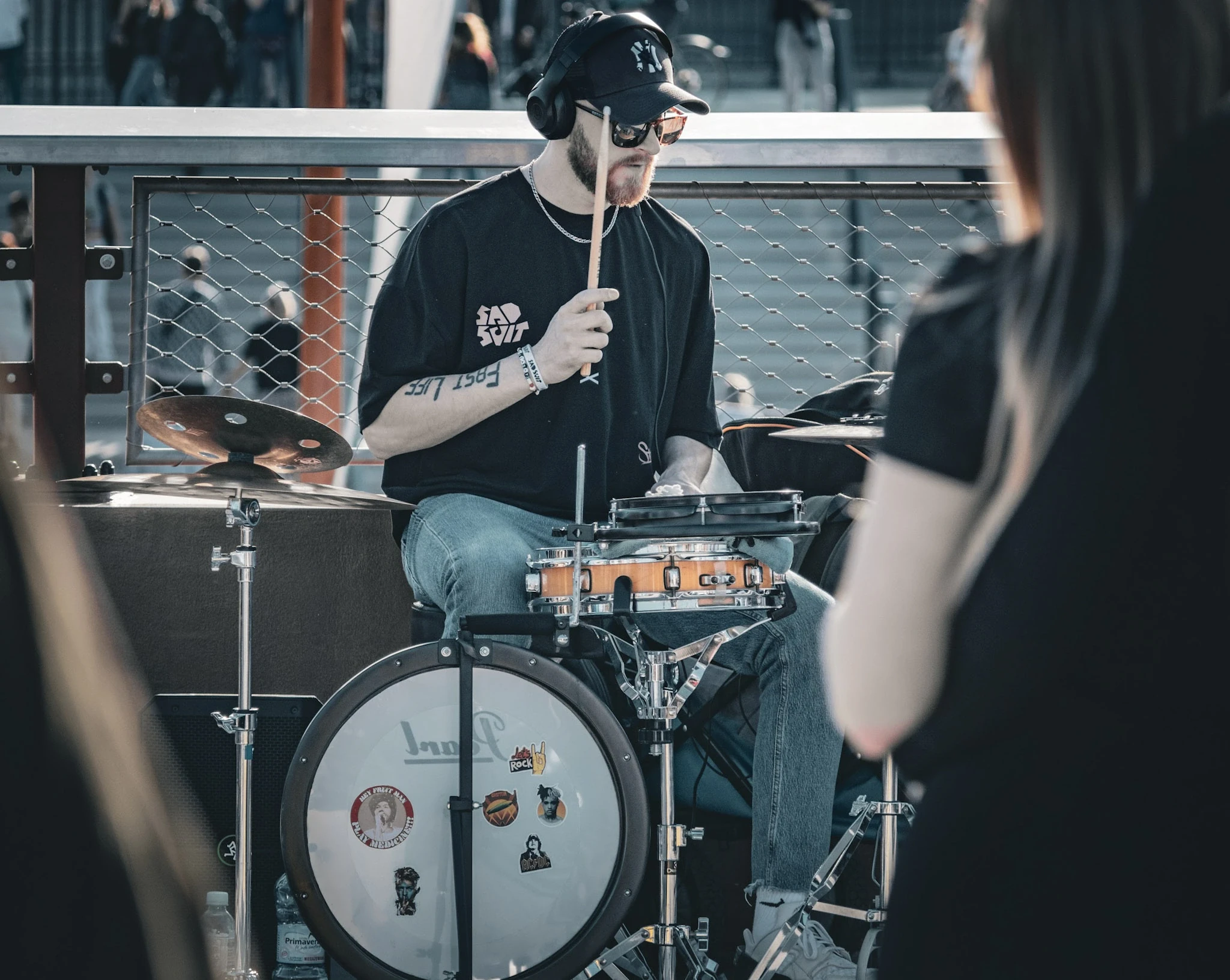A street drummer in a dark shirt playing a compact drum kit.