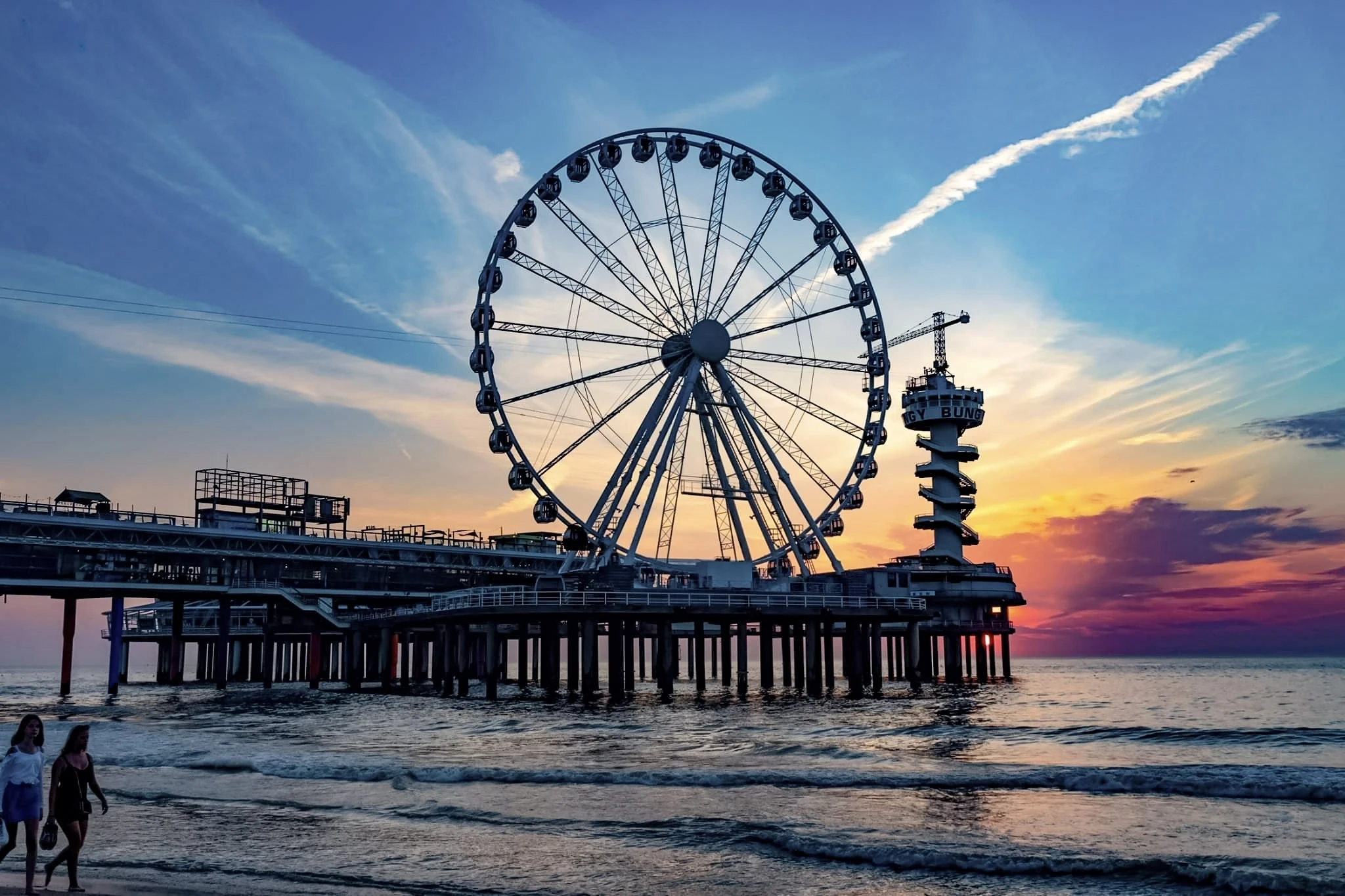 A Ferris wheel on a pier silhouetted against a colourful evening sky.