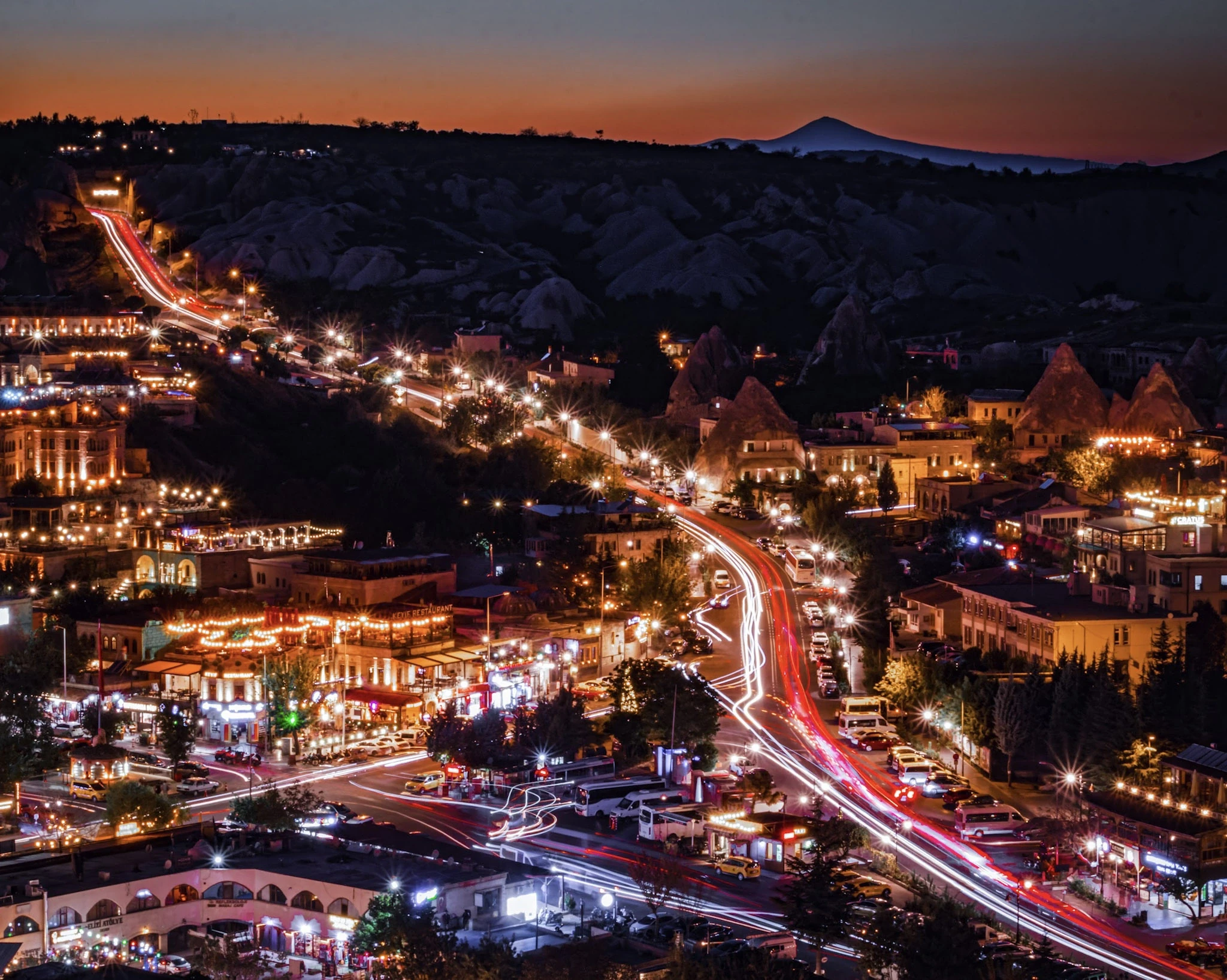 A hillside town glowing at dusk among Cappadocia's rock formations.