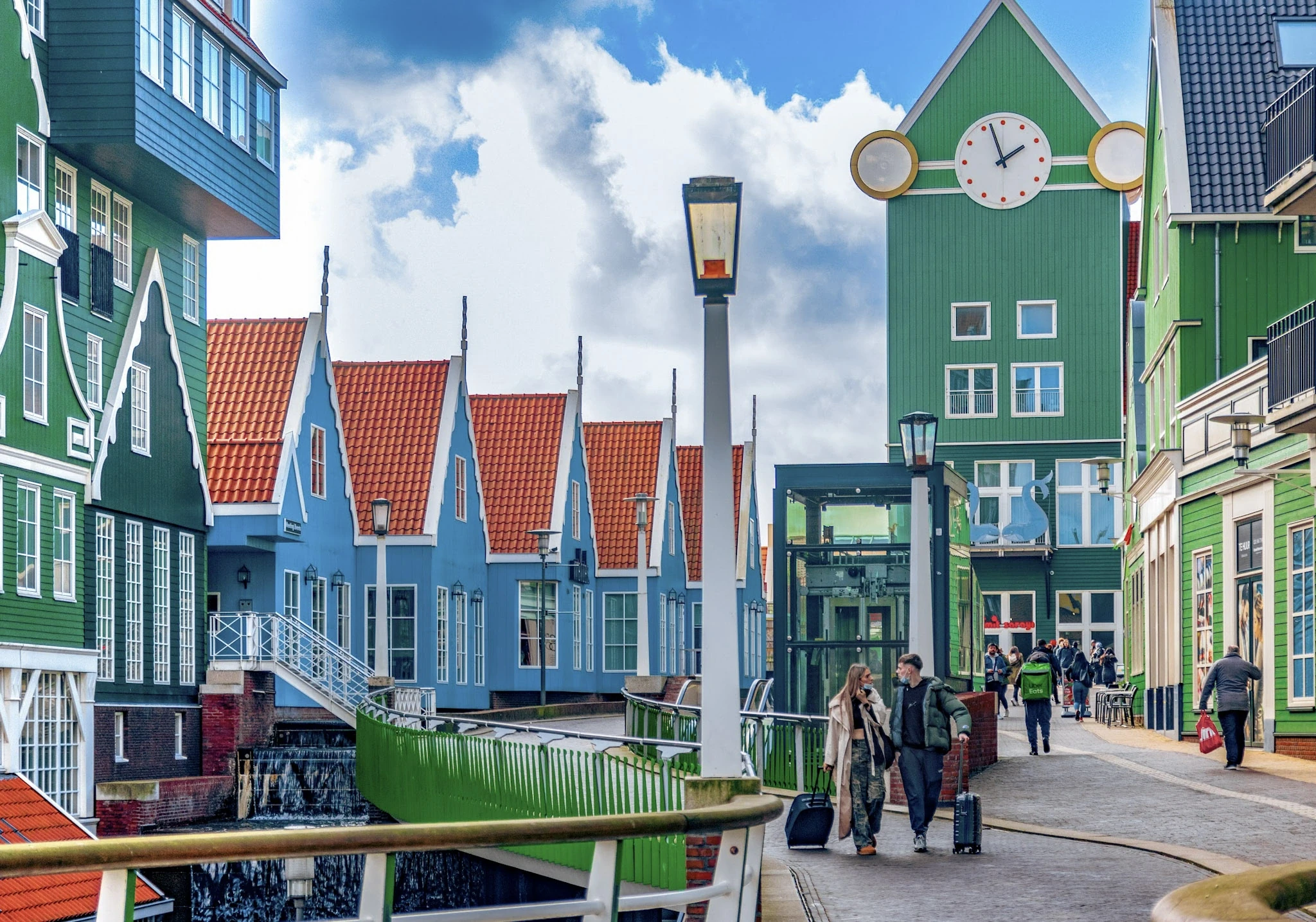 Brightly coloured gabled buildings along a canal-side walkway.
