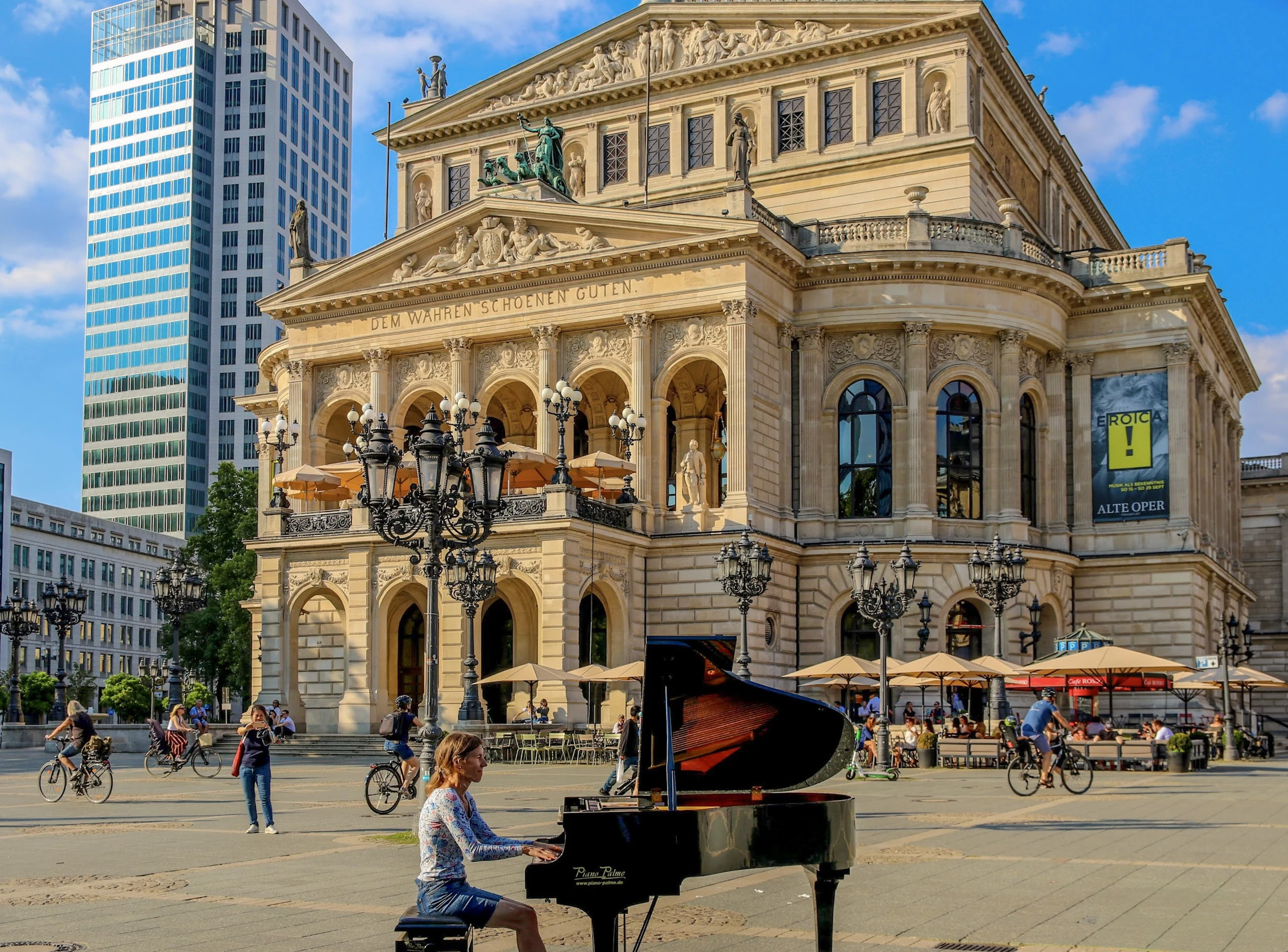 A pianist playing a black grand piano in front of an ornate concert hall.