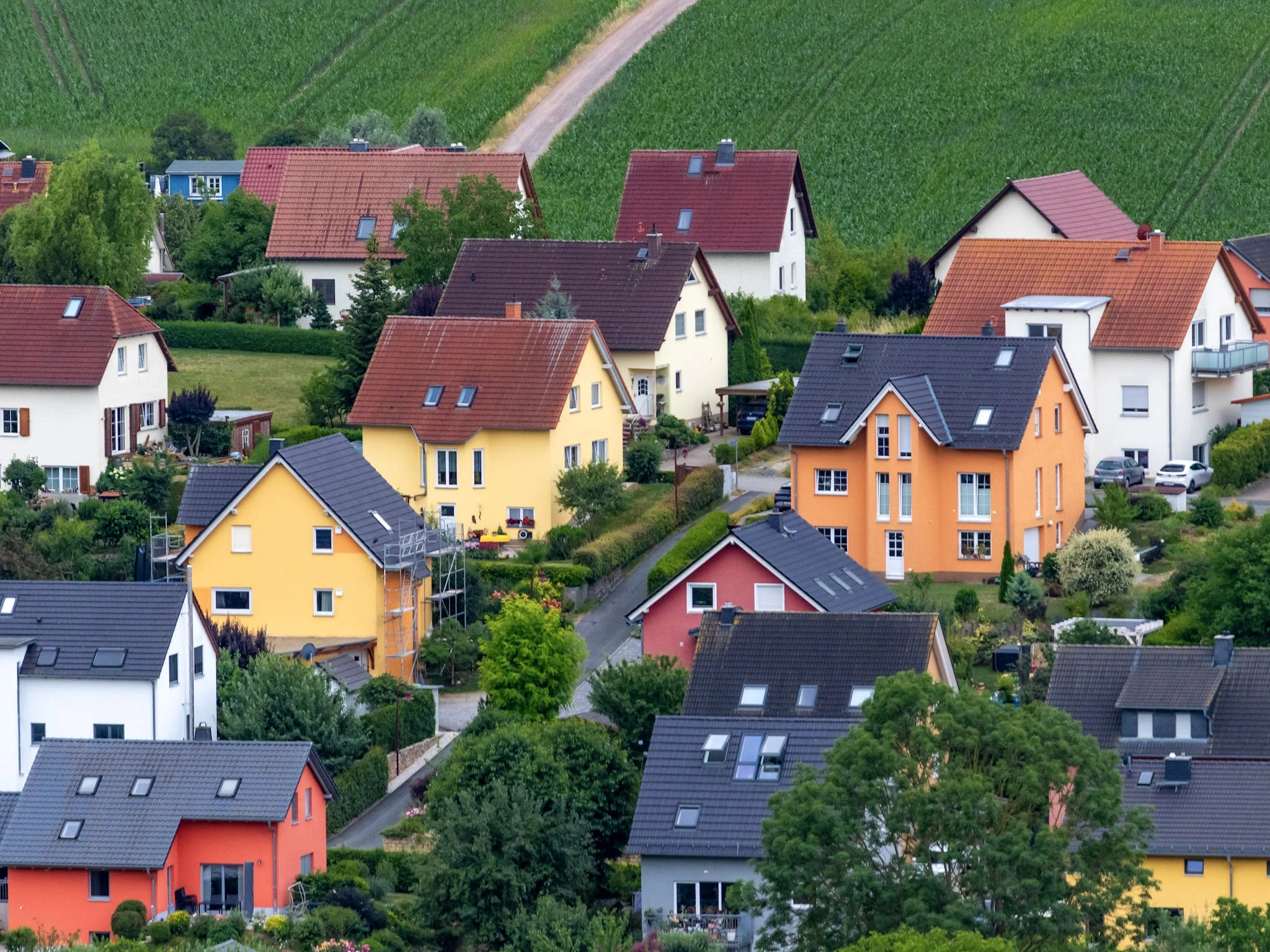 Colourful village houses with red roofs seen from a hillside above.