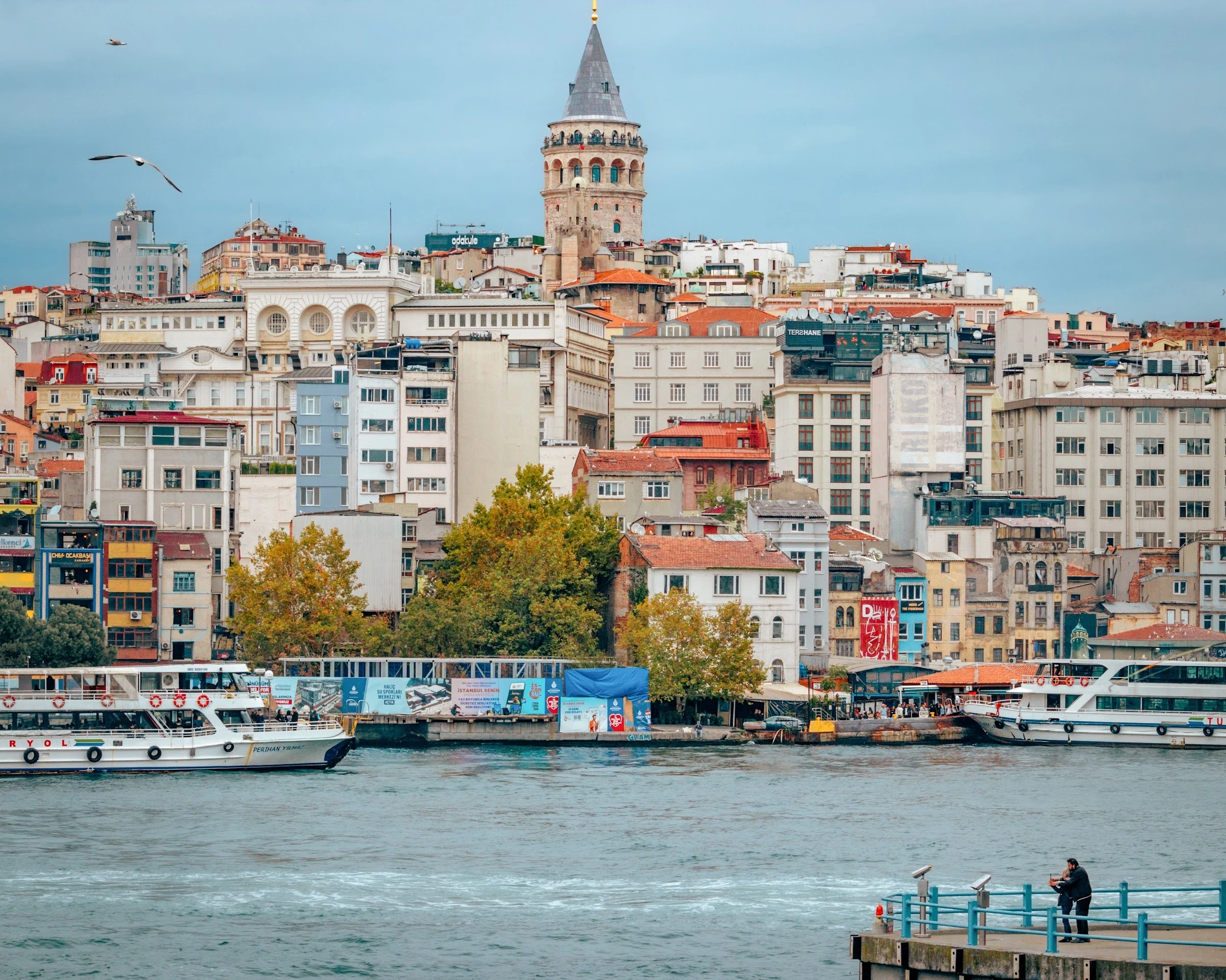The Galata Tower above a dense hillside of Istanbul buildings seen across the water.